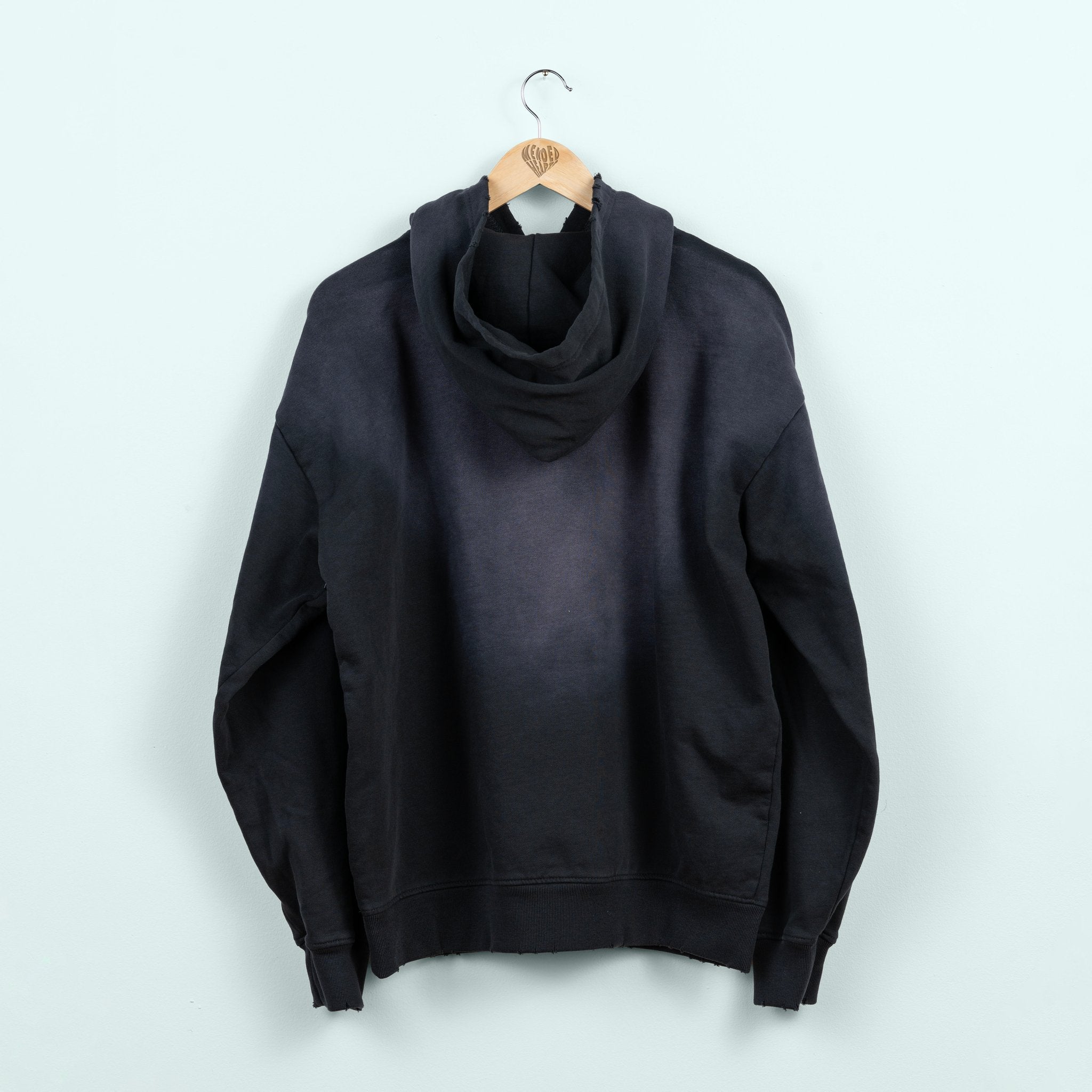 Black hoodie on a hanger against a white background