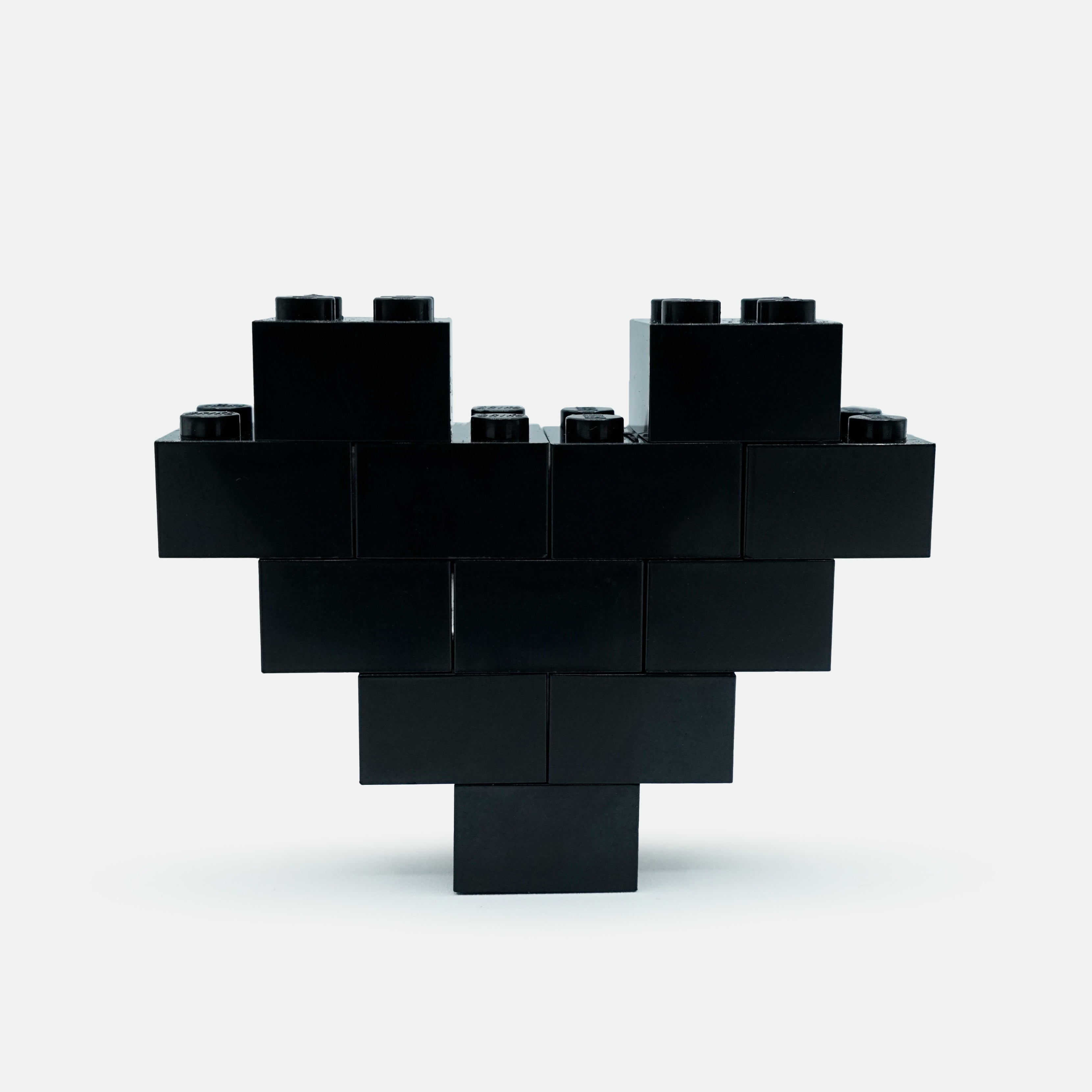 A heart-shaped lapel pin made of black Lego pieces.