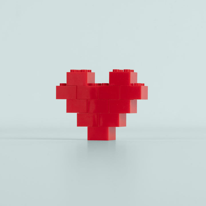 Red heart-shaped object made of interlocking bricks on a light gray background