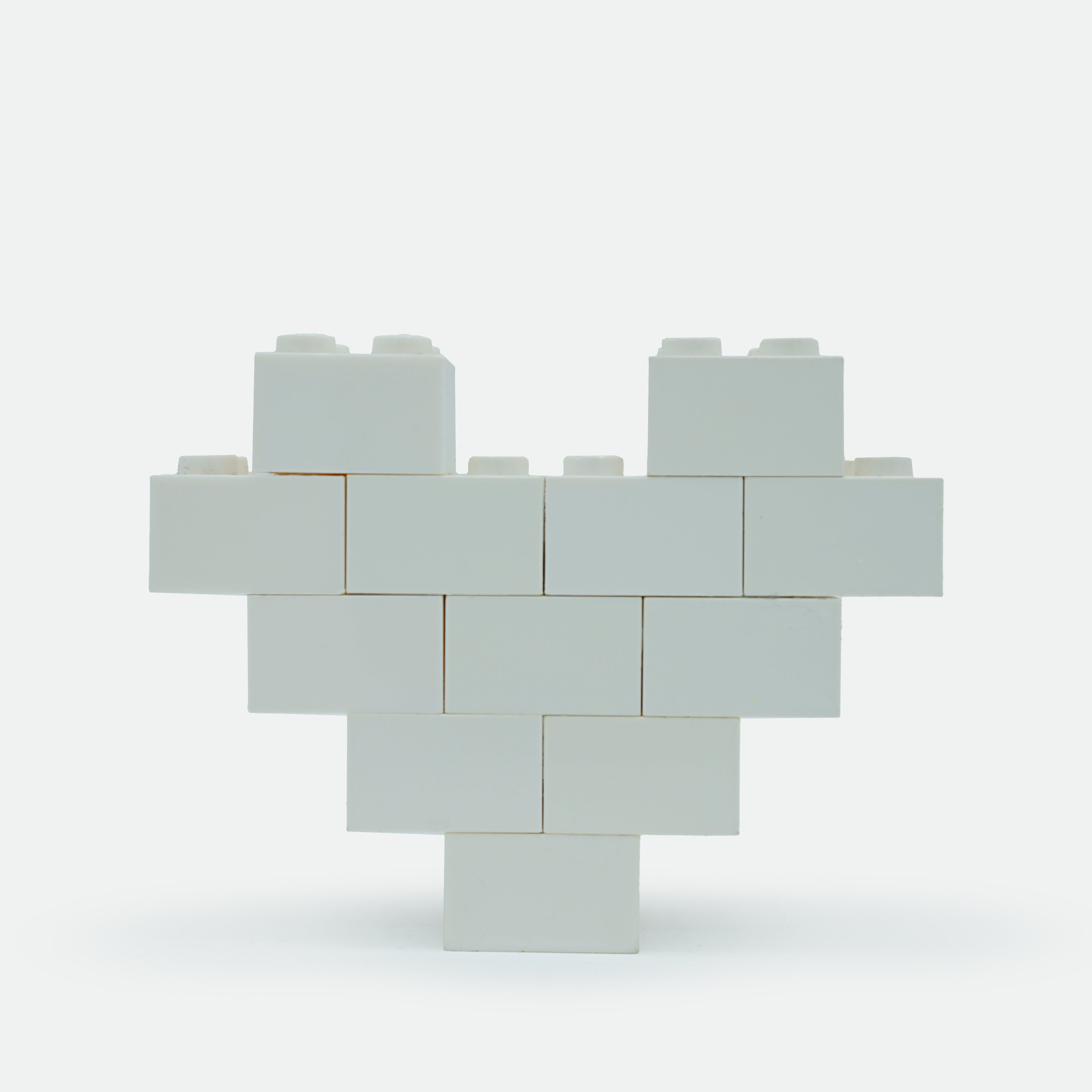 A heart-shaped lapel pin made of black Lego pieces.