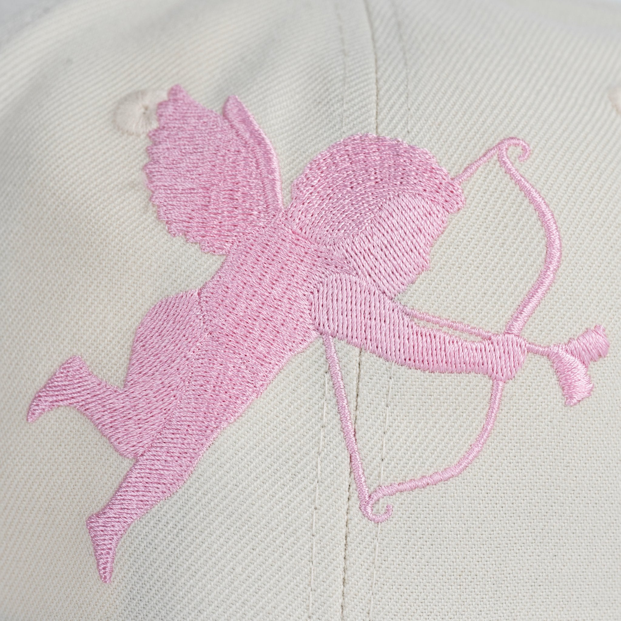 Pink embroidered design of a cupid on a light gray background