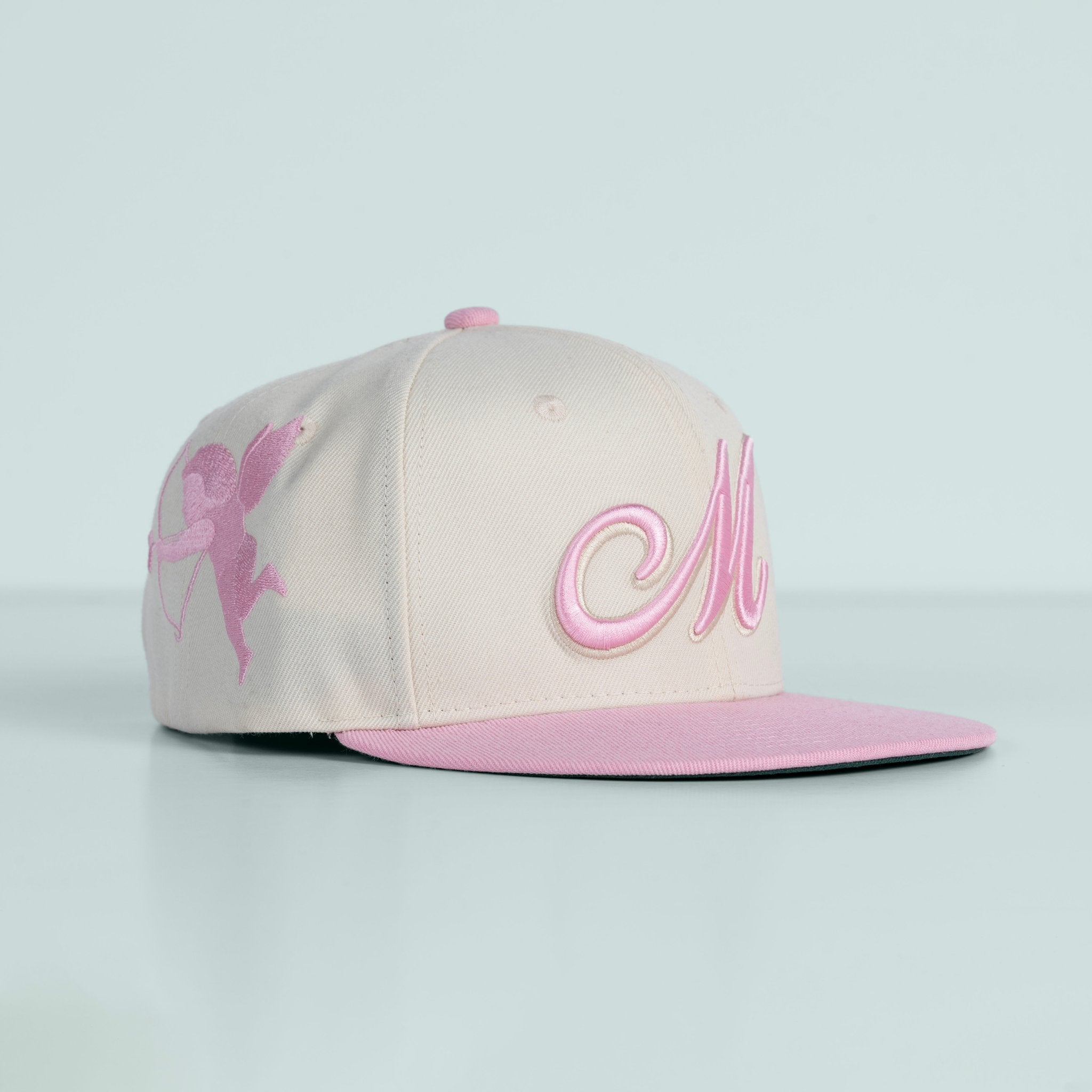 Beige and pink cap with butterfly design on a light gray background