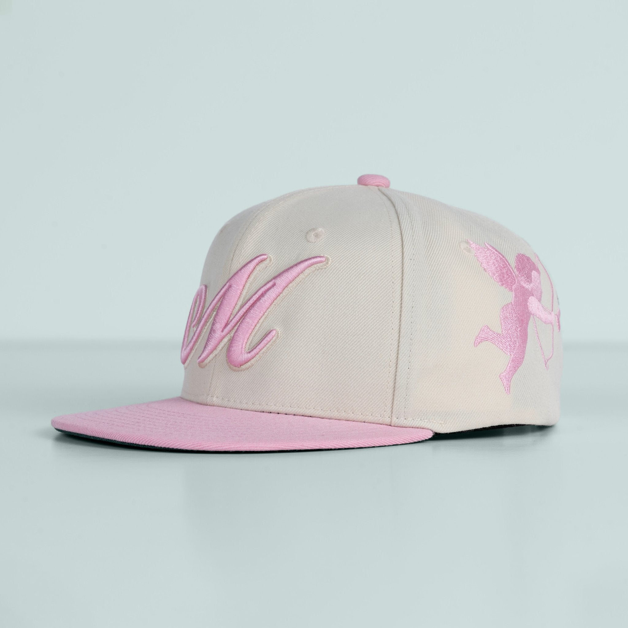 Beige and pink cap with embroidered design on a light gray background
