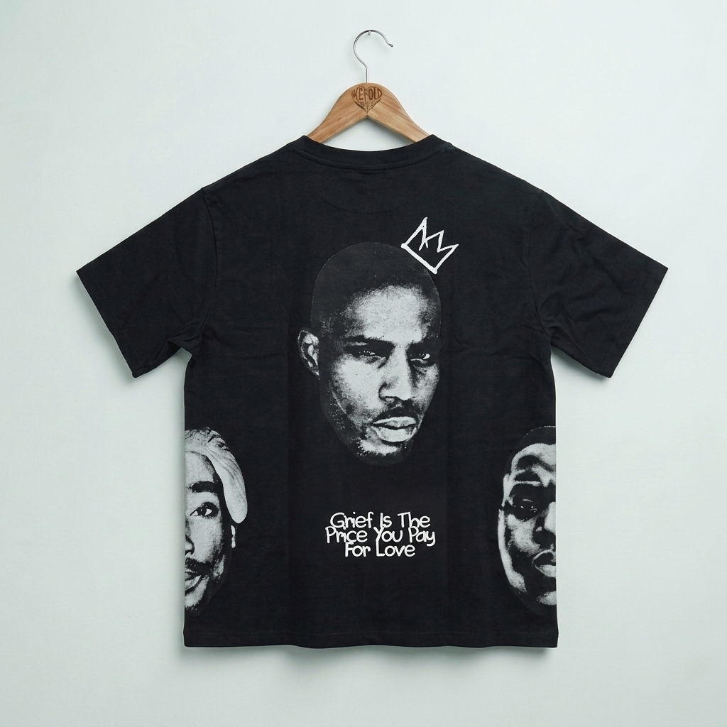 A black short-sleeve t-shirt hanging on a wooden hanger against a light gray wall. The back of the shirt features a large black-and-white graphic print of Tupac Shakur's face with a white crown above his head, white text reading 'Gnet Is The Price You Buy For Love' below, and smaller partial face graphics on the sides.